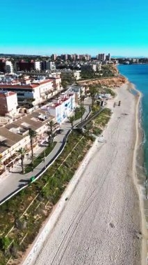 Hava manzaralı Mil Palmeras kıyı şeridi, sahil evleri, gezinti güvertesi, kumlu plaj ve turkuaz Akdeniz açık mavi gökyüzü altında, seyahat, turizm ve emlak için ideal. Costa Blanca, İspanya