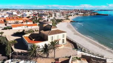 İspanyol Akdeniz kıyısındaki modern marina yakınlarındaki tarihi Torre de la Horada gözlem kulesinin havadan görünüşü kültürel miras, sahil mimarisi ve manzaralı kıyı güzelliğini birleştiriyor. İspanya