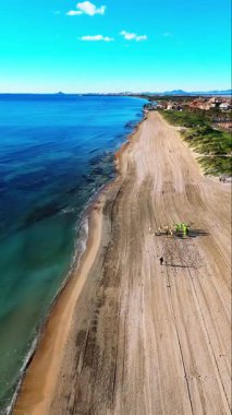 Torre de la Horada, İspanya 'daki sakin sahilin havadan görünüşü, altın kum, berrak turkuaz sular, yumuşak dalgalar ve kıyı bitkileri.