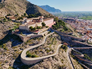 Virajlı yolun havadan görünüşü İspanya 'nın Orihuela kasabasına tepeden bakan engebeli tepenin tepesinde San Miguel Diocesan Papaz Okulu' na çıkıyor. Costa Blanca, Alicante vilayeti
