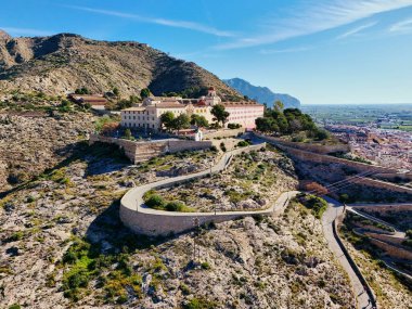 Virajlı yolun havadan görünüşü İspanya 'nın Orihuela kasabasına tepeden bakan engebeli tepenin tepesinde San Miguel Diocesan Papaz Okulu' na çıkıyor. Costa Blanca, Alicante vilayeti
