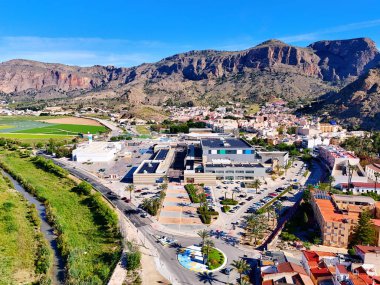 Orihuela 'nın hava manzarası, modern alışveriş merkezi olan şehir, parlak mavi gökyüzünün altındaki dağlar. İspanya, Costa Blanca