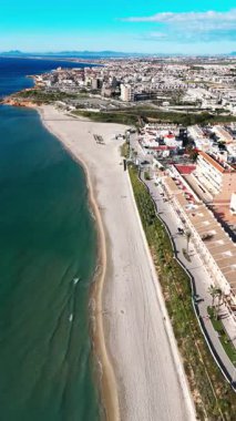 Hava manzaralı Mil Palmeras kıyı şeridi, sahil evleri, gezinti güvertesi, kumlu plaj ve turkuaz Akdeniz açık mavi gökyüzü altında, seyahat, turizm ve emlak için ideal. Costa Blanca, İspanya