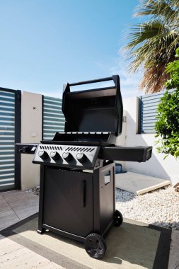 Güneşli verandada modern, parlak, siyah, açık hava, barbekü ızgarası. Yaz yemeği kavramı, arka bahçe yaşam tarzı, barbekü toplantıları.