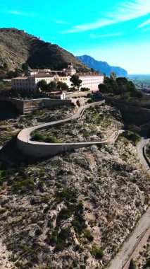 Virajlı yolun havadan görünüşü İspanya 'nın Orihuela kasabasına tepeden bakan engebeli tepenin tepesinde San Miguel Diocesan Papaz Okulu' na çıkıyor. Costa Blanca, Alicante vilayeti
