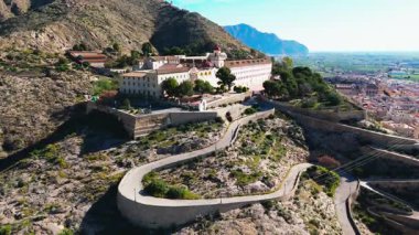 Virajlı yolun havadan görünüşü İspanya 'nın Orihuela kasabasına tepeden bakan engebeli tepenin tepesinde San Miguel Diocesan Papaz Okulu' na çıkıyor. Costa Blanca, Alicante vilayeti. Seyahat hedefi kavramı