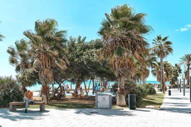 Torrevieja, Spain - September 28, 2024: Scenic view of coastal promenade in Torrevieja with children playground, and people relaxing near Mediterranean Sea. Touristic places concept