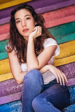 Canlı çizgili bir duvarda oturan mutlu bir birey..