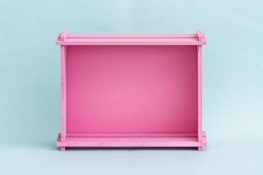 Açık mavi arkaplana karşı parlak pembe ahşap kutu, minimalist tasarım.