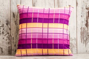 Canlı kareli desenli dekoratif yastık, pembe, mor ve sarı çizgili zengin bir palet sergiliyor..