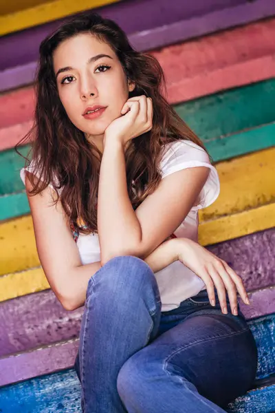 Canlı çizgili bir duvarda oturan mutlu bir birey..