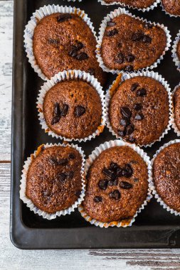 Üstünde çikolata parçacıkları olan taze çikolatalı kek tepsisi beyaz ahşap masaya konur..