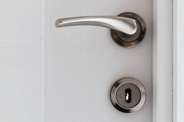 Gümüş kapı kolu kapalı beyaz bir kapı, yakın görüş, basit ve temiz iç mekan..