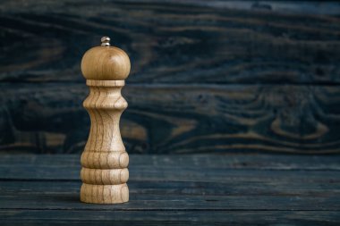 Koyu mavi ahşap bir yüzeye yerleştirilmiş ahşap biber değirmeni..