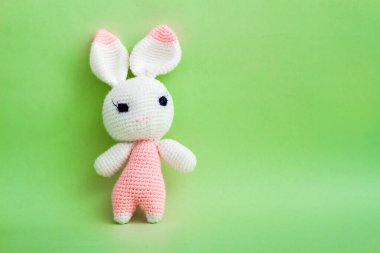 Narin tığ işi amigurumi tığ işi tavşan bebek yeşil bir tuval üzerinde sanatsal sergileniyor..