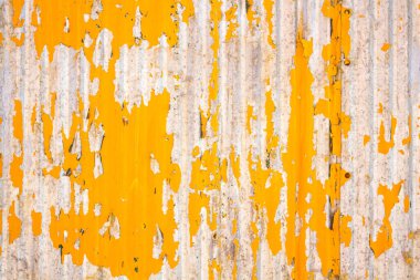 Close up of a weathered corrugated metal surface with peeling yellow paint, revealing rust and wear underneath. clipart
