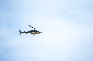 Açık mavi gökyüzünde uçan helikopter, havada donmuş gibi görünüyor..