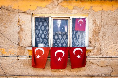Türkiye 'de eski, yıpranmış sarı bir duvara dayanmış Türk bayraklarının asılı olduğu pencere.