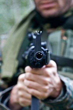 kamuflaj kumaş giyen bir asker bir hava silah çekmeye yönlendiriyor.