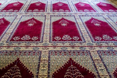 Türkiye 'de bir camide, karmaşık tasarımları olan geleneksel kırmızı ve beyaz desenli bir halıyı kapatın.