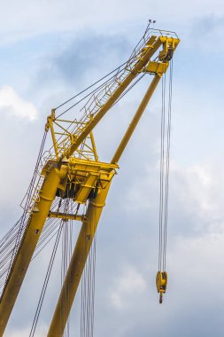 Büyük sarı endüstriyel vinç bulutlu bir gökyüzüne karşı kablolarla.