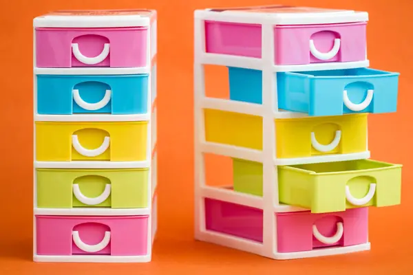stock image Colorful storage drawers in vibrant hues placed against an orange background offering a cheerful and practical organization solution for various items.