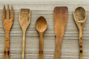 Ahşap bir yüzeye yerleştirilmiş kaşık, çatal ve spatuladan oluşan ahşap mutfak aletleri..