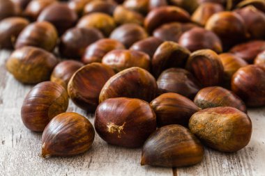 Kestaneler, sonbahar ve mevsimsel gösteriler için mükemmel bir doğal ve dünyevi dokunuş sağlayan kırsal ahşap bir masaya saçılmış..