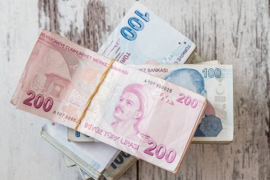 Türk lirası banknotları, finans ve ekonomiyi temsil eden beyaz ahşap bir masaya yığılmış çeşitli banknotlar halinde.