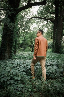 Genç bir adam karanlık bir ormanda yürüyor.