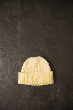 Gri arka planda küçük örülü sıcak bir şapka.