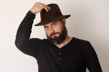 Hafif arka planda kahverengi şapkalı sakallı bir adam.