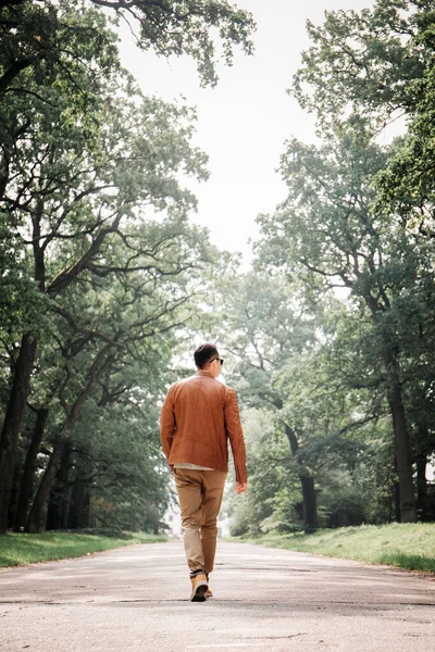 一个年轻英俊的小伙子正带着大树在宽阔的路上走着 — 图库照片