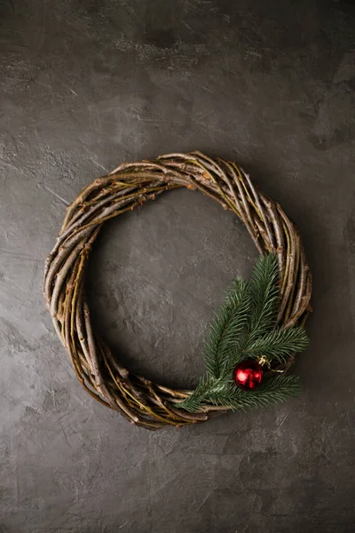 A wreath of branches with a ball and a spruce branch on a gray background. Christmas concept