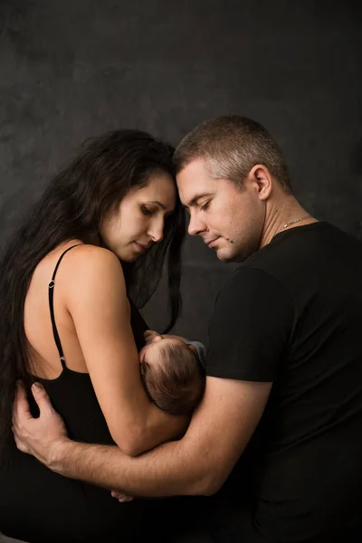 Jonge Ouders Met Hun Kleine Baby Een Donkere Achtergrond Achteraanzicht — Stockfoto