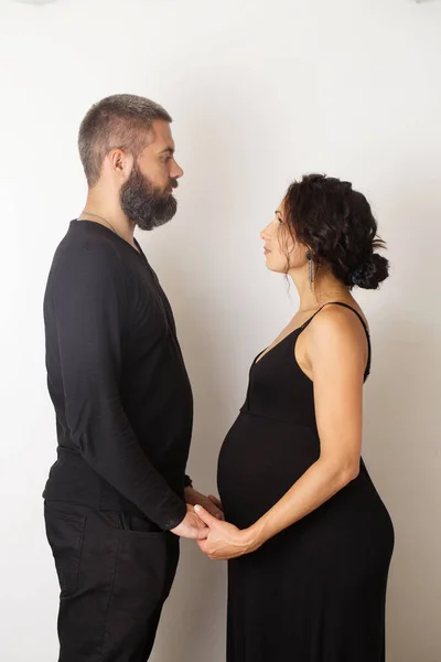 A pregnant woman with a man on a light background