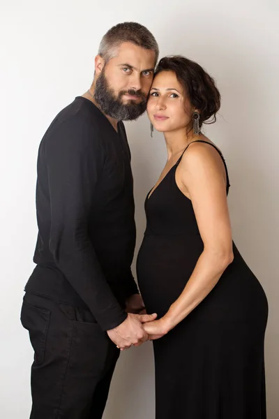 A pregnant woman with a man on a light background