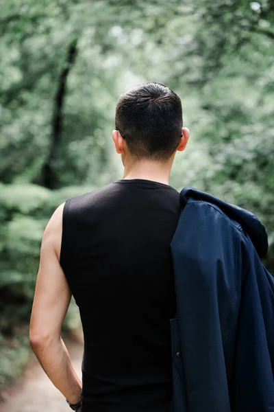 stock image a brutal man in black clothes walks down the alley in the foggy forest