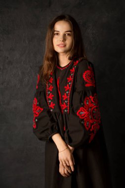 Siyah işlemeli elbisesi olan, siyah arka planda güzel bir Ukraynalı kadın.