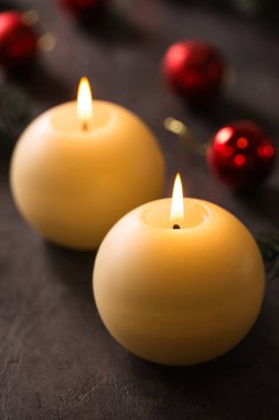 Koyu arkaplanda Noel süsü olan iki büyük yuvarlak mum.