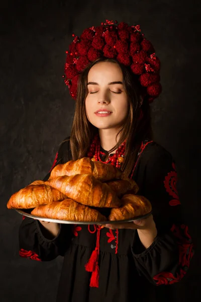 Ουκρανή Γυναίκα Εθνικό Φόρεμα Κρατά Ένα Δίσκο Ρόδινα Κρουασάν Σκούρο — Φωτογραφία Αρχείου