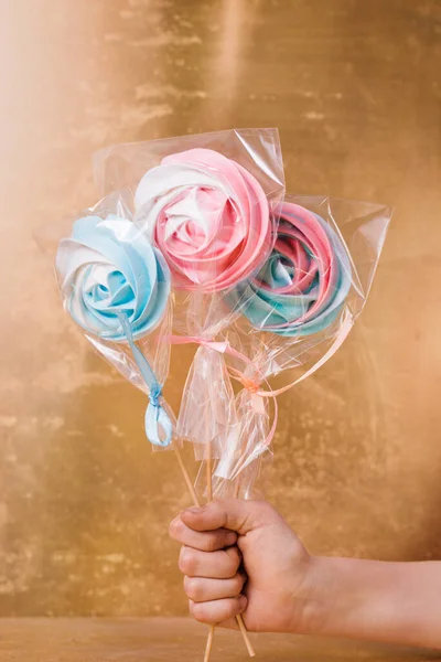 A colorful vegetarian aquafaba meringue candy on a stick on a golden background
