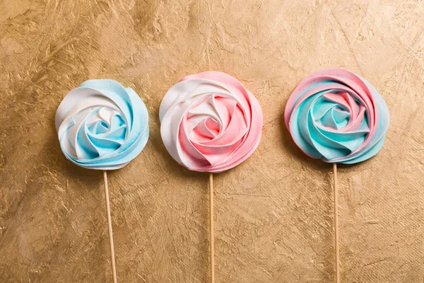 A colorful vegetarian aquafaba meringue candy on a stick on a golden background