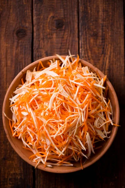 Winter salad of carrots and celery in a bowl on a wooden background