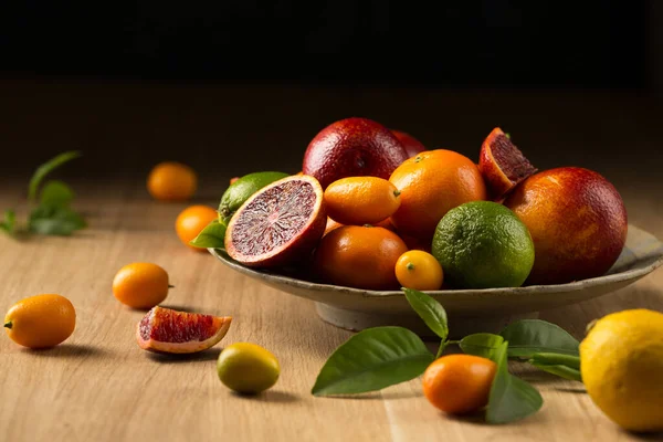 Tahta bir masada büyük bir tabak sulu narenciye.