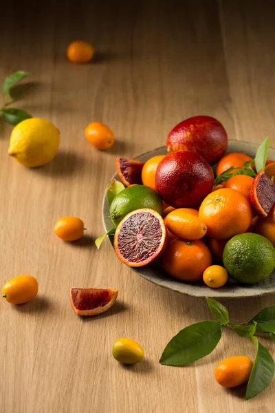 Tahta bir masada büyük bir tabak sulu narenciye.