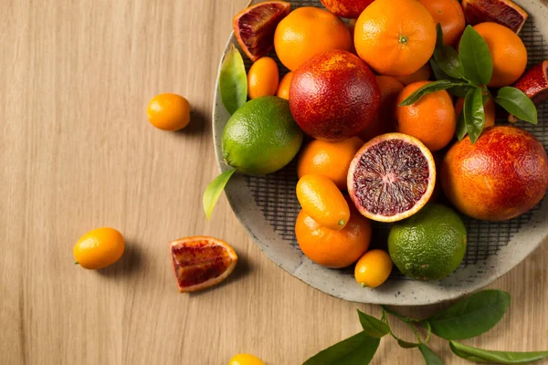 Tahta bir masada büyük bir tabak sulu narenciye.