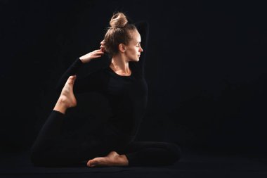 Kız yoga yapıyor, siyah arka planda portre çiziyor.