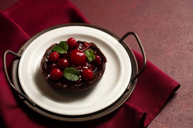 Kirazlı çikolatalı tatlı ve şarap arkaplanlı bir tabakta nane şekeri.