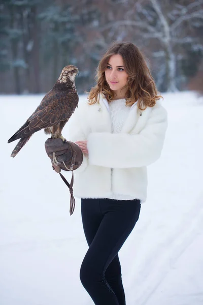 毛皮のコートの女の子は冬に手に鷹を持っています — ストック写真